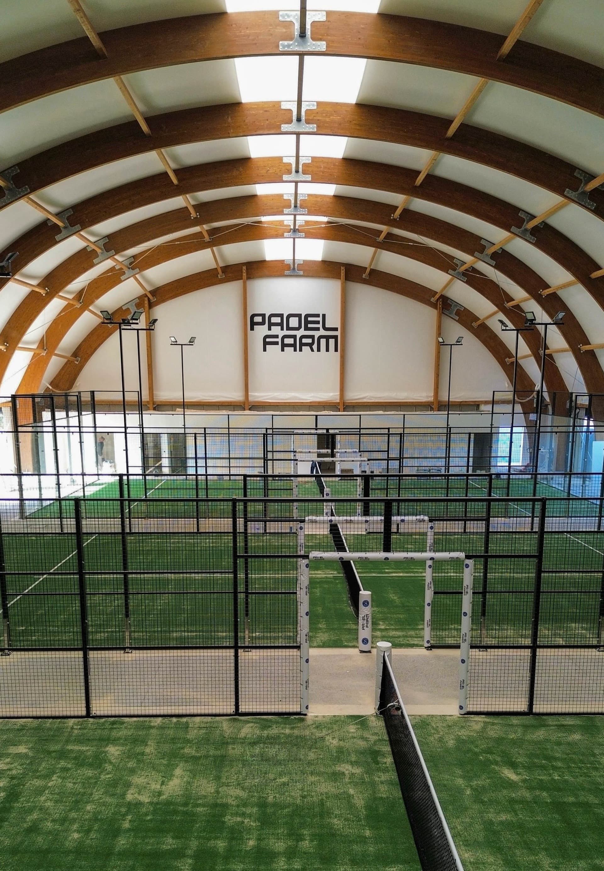 Vue intérieure des trois pistes de padel avec charpente bois